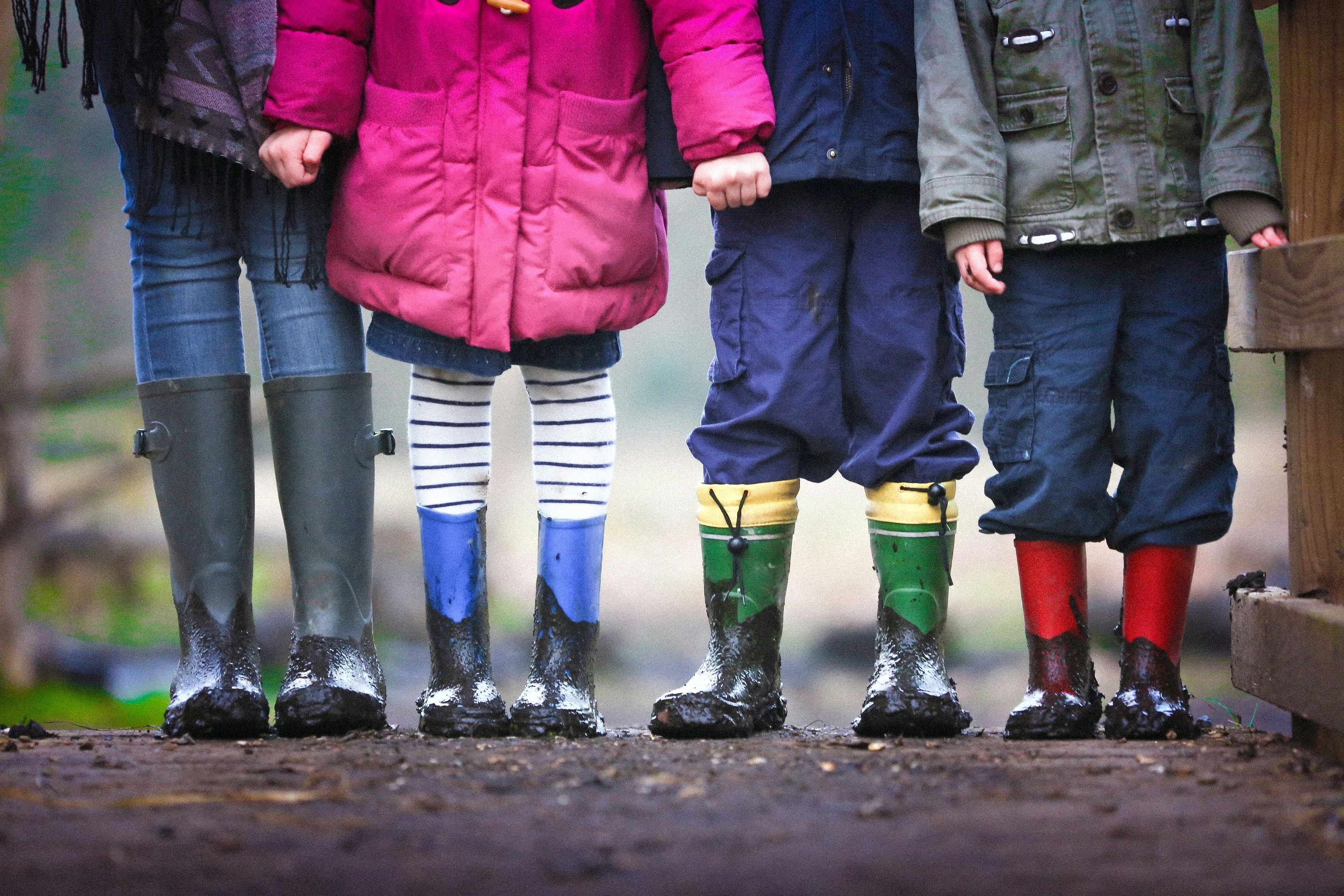 Kinder stehen in Gummistiefeln im Matsch